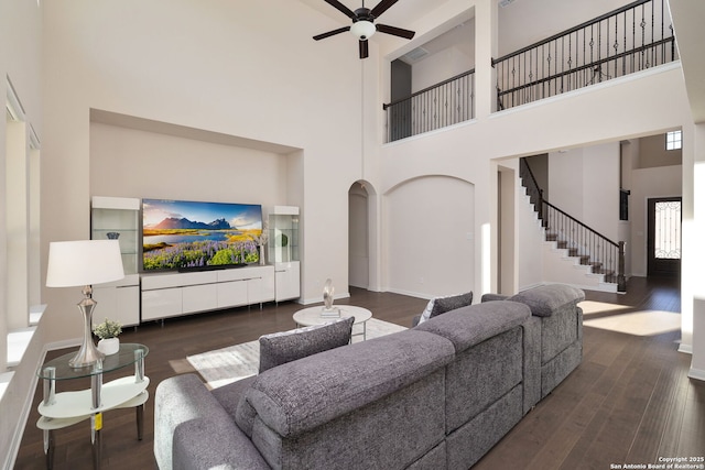 living room featuring a towering ceiling, dark wood-type flooring, and ceiling fan