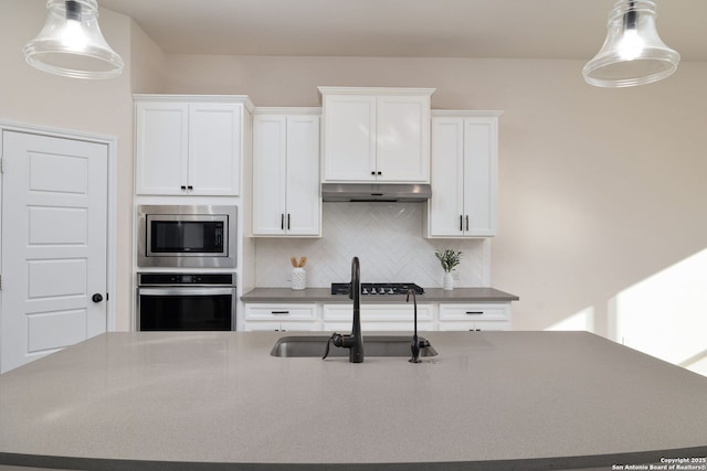 kitchen featuring stainless steel appliances, sink, pendant lighting, and decorative backsplash