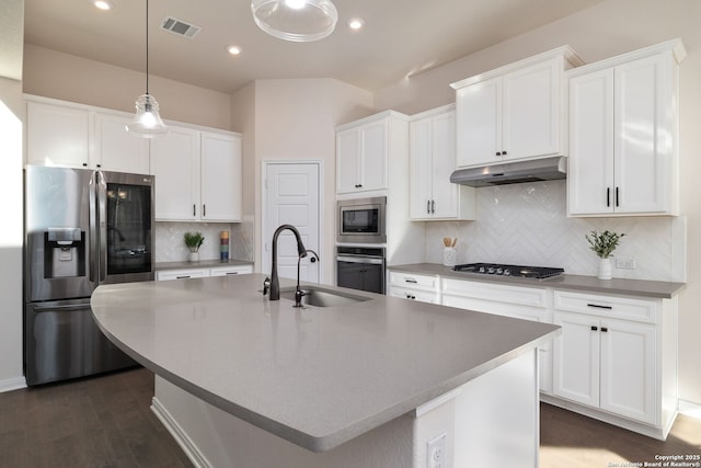 kitchen with stainless steel appliances, a kitchen island with sink, sink, and backsplash