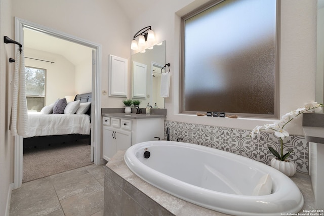 bathroom featuring lofted ceiling, tiled tub, and vanity