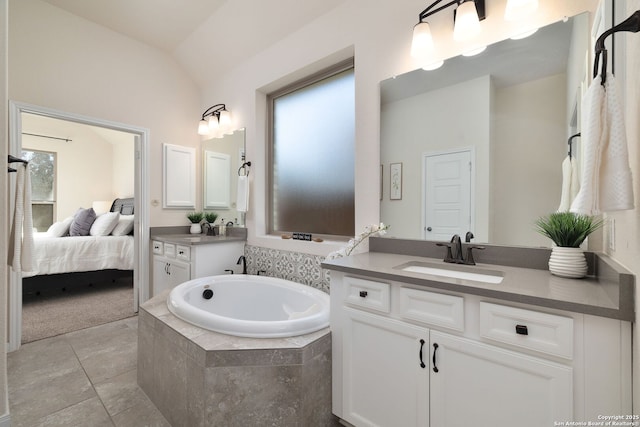 bathroom with vaulted ceiling, a healthy amount of sunlight, a relaxing tiled tub, and vanity