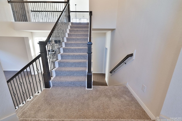 stairway with a towering ceiling, a wealth of natural light, and carpet flooring