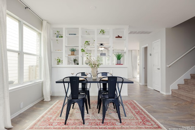 dining space with visible vents, plenty of natural light, stairway, and wood finished floors