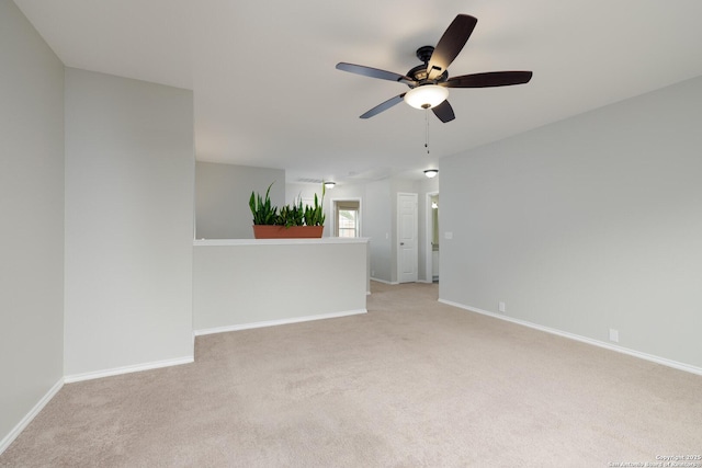 unfurnished room featuring a ceiling fan, light carpet, and baseboards