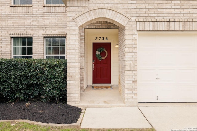 view of exterior entry featuring brick siding and an attached garage