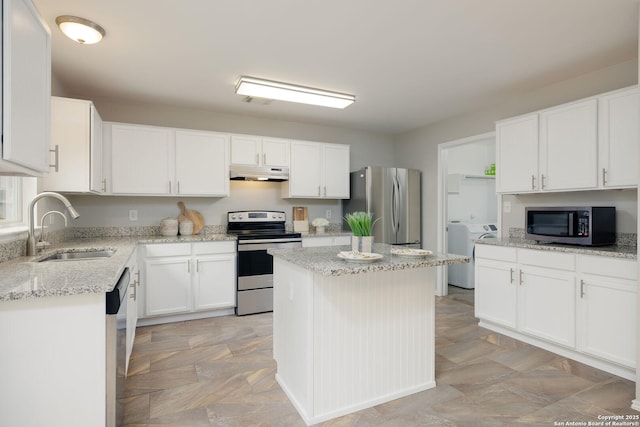 kitchen featuring appliances with stainless steel finishes, a center island, under cabinet range hood, white cabinetry, and a sink