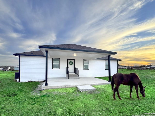 back house at dusk with a lawn