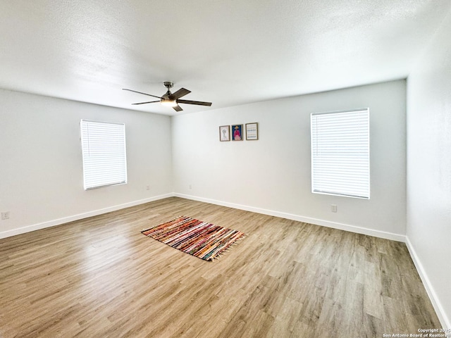 unfurnished room with ceiling fan, light hardwood / wood-style flooring, and a textured ceiling