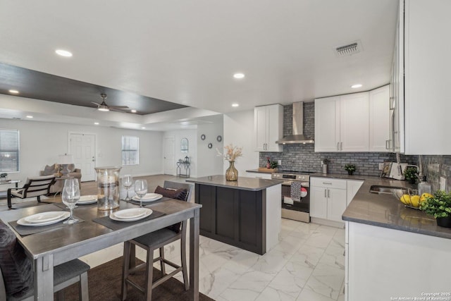 kitchen with white cabinets, a kitchen island, wall chimney exhaust hood, and stainless steel electric range