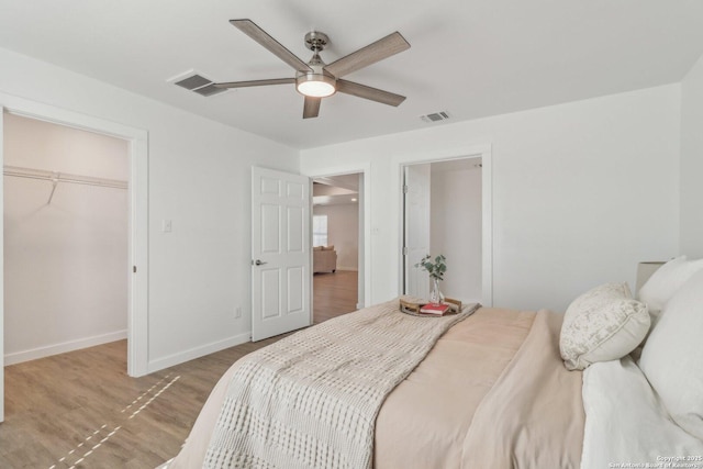 bedroom featuring ceiling fan, wood-type flooring, a spacious closet, and a closet