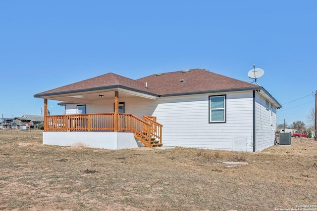 rear view of house featuring central AC and a lawn