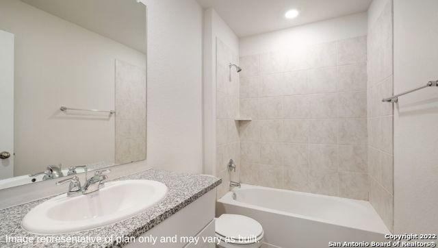 full bathroom featuring tiled shower / bath combo, vanity, and toilet