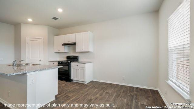 kitchen with dark hardwood / wood-style floors, sink, white cabinets, light stone counters, and black gas range