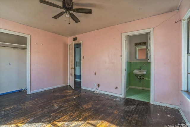 unfurnished bedroom featuring ceiling fan, dark hardwood / wood-style floors, ensuite bath, and a closet