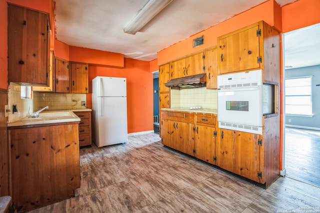 kitchen featuring tasteful backsplash, white appliances, tile countertops, and sink