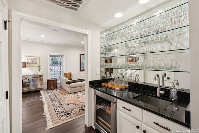 bar with sink, dark hardwood / wood-style floors, white cabinets, beverage cooler, and dark stone counters