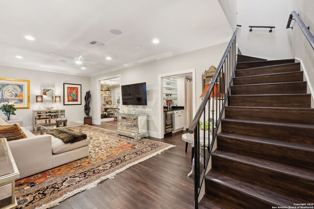 living room with wine cooler, ceiling fan, ornamental molding, and dark wood-type flooring