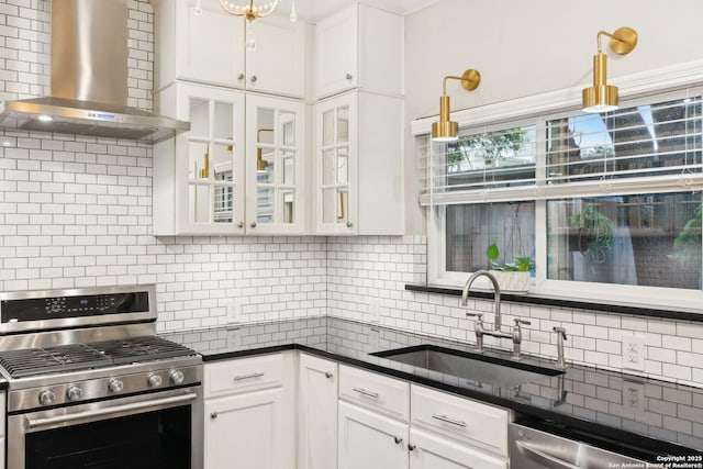 kitchen featuring wall chimney exhaust hood, sink, appliances with stainless steel finishes, decorative backsplash, and white cabinets