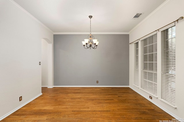 unfurnished dining area with an inviting chandelier, ornamental molding, and hardwood / wood-style floors