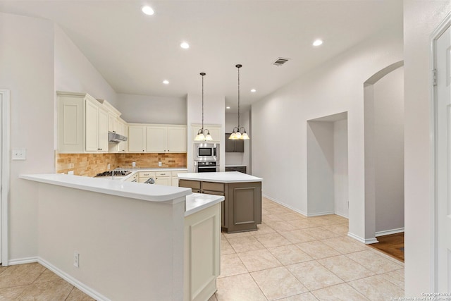 kitchen featuring tasteful backsplash, a center island, hanging light fixtures, light tile patterned floors, and kitchen peninsula