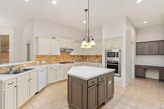 kitchen featuring sink, backsplash, hanging light fixtures, stainless steel appliances, and a kitchen island