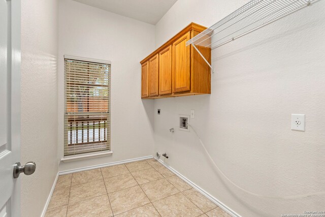 clothes washing area featuring gas dryer hookup, light tile patterned floors, electric dryer hookup, hookup for a washing machine, and cabinets