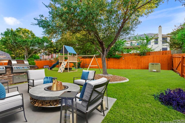 view of yard featuring an outdoor kitchen, an outdoor fire pit, a playground, and a patio