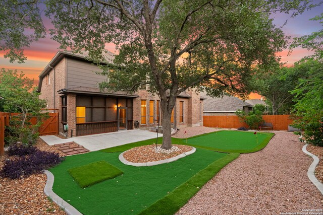 back house at dusk featuring a patio area