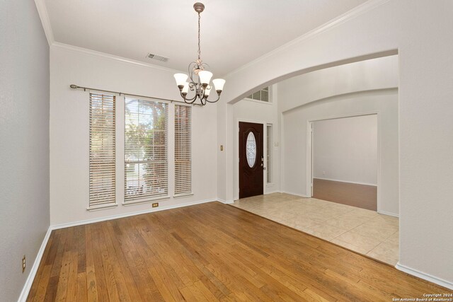 entryway with crown molding, hardwood / wood-style floors, and an inviting chandelier