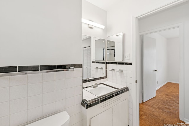 bathroom with vanity, parquet flooring, tile walls, and toilet