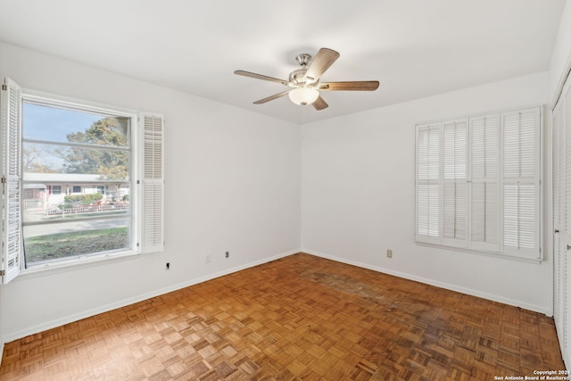 unfurnished room with ceiling fan and dark parquet flooring