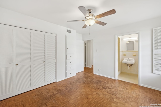 unfurnished bedroom featuring ensuite bath, light parquet flooring, and ceiling fan