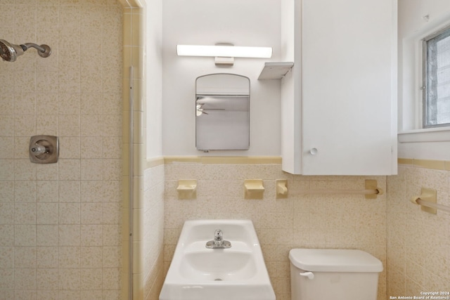 bathroom with tiled shower, sink, tile walls, and toilet