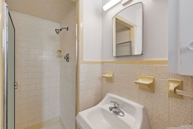 bathroom with walk in shower, sink, and tile walls