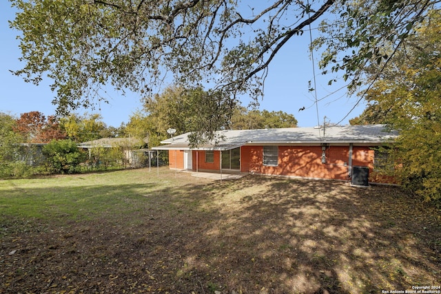 back of property featuring cooling unit and a lawn