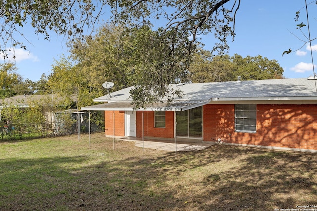 back of property with a patio area and a lawn