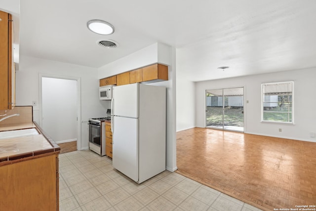 kitchen featuring sink, tile counters, white appliances, and decorative backsplash