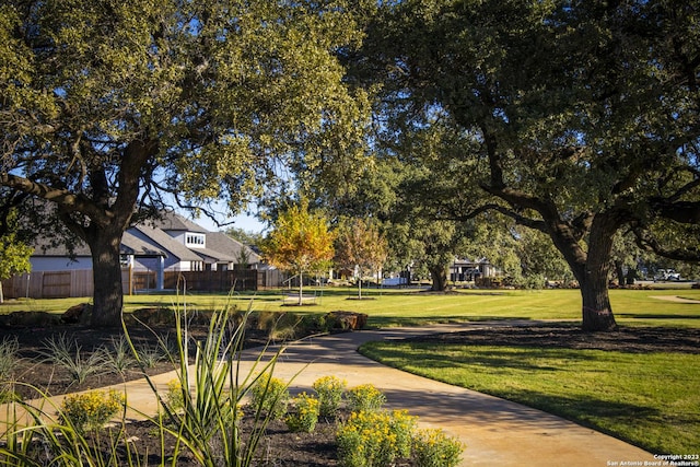 view of property's community with a lawn and fence