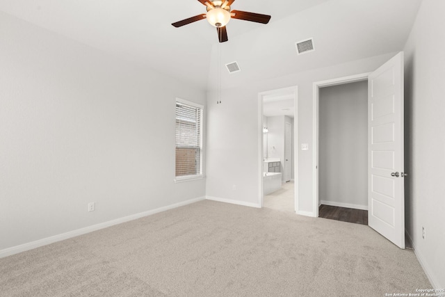 unfurnished bedroom with light colored carpet, vaulted ceiling, visible vents, and baseboards