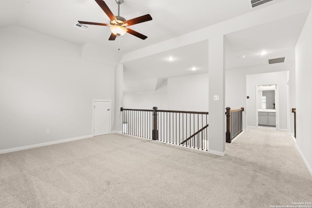 unfurnished room with lofted ceiling, light carpet, visible vents, and baseboards