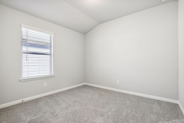 carpeted spare room featuring a healthy amount of sunlight and lofted ceiling