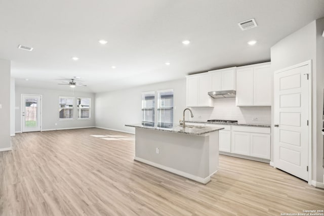 kitchen featuring white cabinetry, sink, a kitchen island with sink, and light stone counters