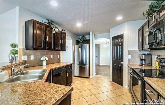 kitchen featuring sink, light tile patterned floors, dark brown cabinets, black appliances, and a textured ceiling