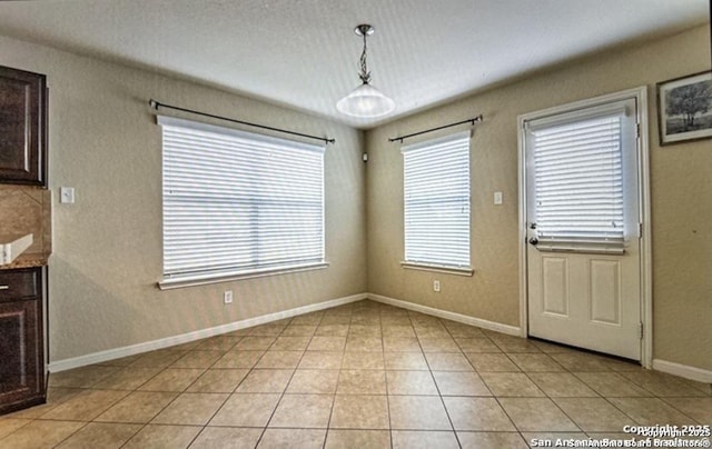 unfurnished dining area with light tile patterned flooring, a healthy amount of sunlight, and a textured ceiling