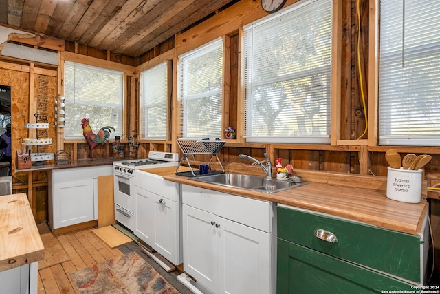 kitchen featuring sink, butcher block countertops, light wood-type flooring, white gas range, and white cabinets