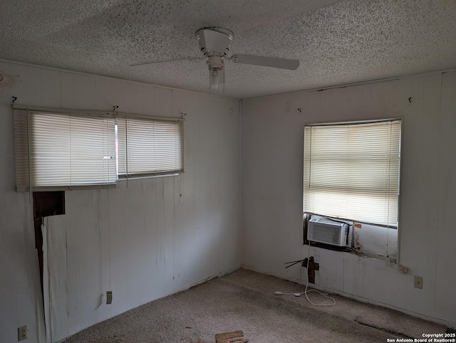 carpeted empty room featuring ceiling fan, wooden walls, cooling unit, and a textured ceiling