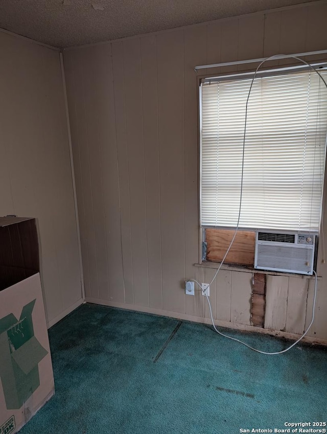 carpeted spare room with cooling unit, a textured ceiling, and wood walls