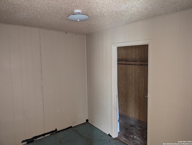 empty room featuring wooden walls and a textured ceiling