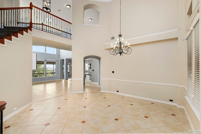 tiled entryway with a towering ceiling and a notable chandelier