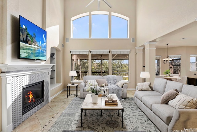 living room with a chandelier, light tile patterned floors, built in features, a fireplace, and decorative columns